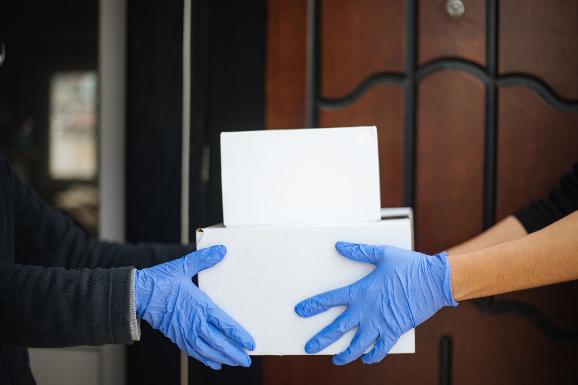 Courier in protective mask delivers parcel to client